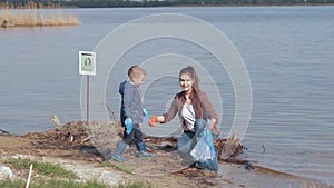 Environmental problems solutions, boy helps woman volunteer activist clean up dirty river waterfront from plastic trash