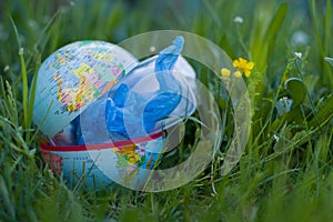 Environmental protection. Garbage bags inside an open globe on the grassy blurred background. Planet pollution.
