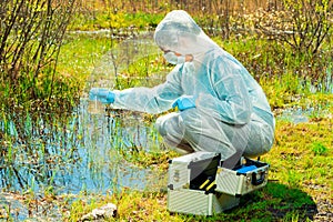 environmentalist on the shore of a forest lake takes water samples after an environmental