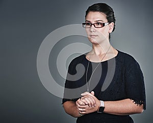 Envisioning all that she aspires to be. Studio shot of a confident young businesswoman posing against a grey background.