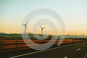 Eolian energy, Go green, Wind turbines along the road at sunset