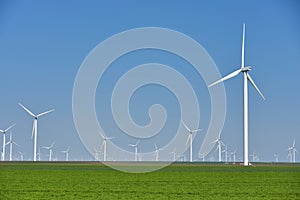 Eolian farm renewable energy in fresh green field against clear blue sky