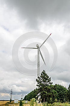 Eolian field and wind turbines farm, near yellow fllowers field, clouds blue sky