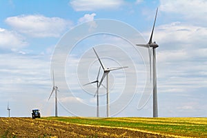 Eolian wind turbine with plough tractor in the background