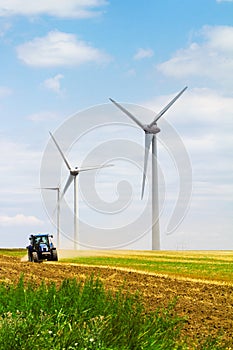 Eolian wind turbine with plough tractor in the background
