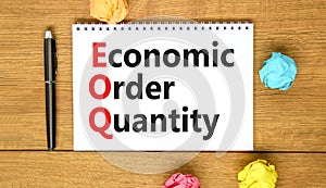 EOQ economic order quantity symbol. Concept words EOQ economic order quantity on white note on beautiful wooden table wooden