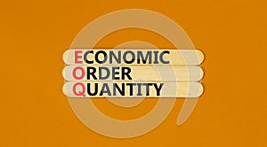 EOQ economic order quantity symbol. Concept words EOQ economic order quantity on wooden stick on a beautiful orange table orange