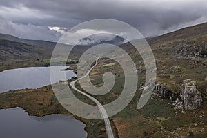 Epic aerial flying drone landscape image of Snowdon Massif viewed from above Llynau Mymber during Autumn sunset with dramatic sky