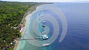 Epic aerial top down of crystal clear coral reefs under wooden pier on Gili Meno Island during sunshine