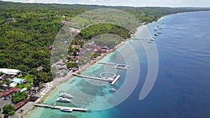 Epic aerial top down of crystal clear coral reefs under wooden pier on Gili Meno Island during sunshine