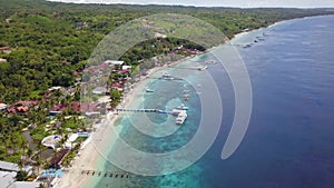 Epic aerial top down of crystal clear coral reefs under wooden pier on Gili Meno Island during sunshine