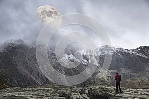 Epic digital composite image of Supermoon above mountain range giving very surreal fantasy look to the dramatic landscape image photo
