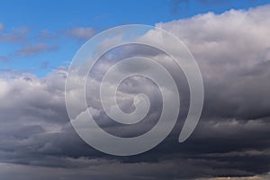 Epic Dramatic storm dark grey cumulus rain clouds against blue sky background texture