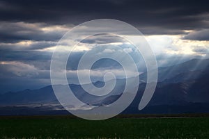 Epic, dramatic sunrays seeping through the clouds over the Andes Mountains in Mendoza, Argentina, on a dark, cloudy day