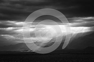 Epic, dramatic sunrays seeping through the clouds over the Andes Mountains in Mendoza, Argentina, on a dark, cloudy day.