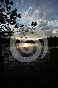 An epic lake view in Sweden near GlommerstrÃ¤sk. with open and cloudy sky and reflecting lake surface and a setting sun