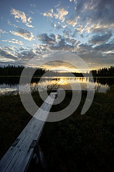 An epic lake view in Sweden near GlommerstrÃ¤sk. with open and cloudy sky and reflecting lake surface and a setting sun