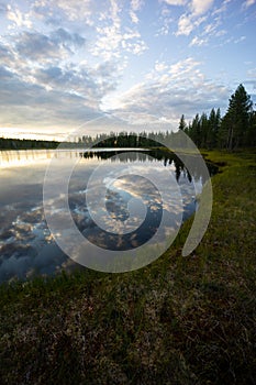 An epic lake view in Sweden near GlommerstrÃ¤sk. with open and cloudy sky and reflecting lake surface and a setting sun