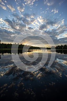 An epic lake view in Sweden near GlommerstrÃ¤sk. with open and cloudy sky and reflecting lake surface and a setting sun