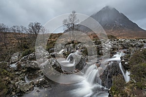 Epic landscape image of Buachaille Etive Mor waterfall in Scottish highlands on a Winter morning with long exposure for smooth photo