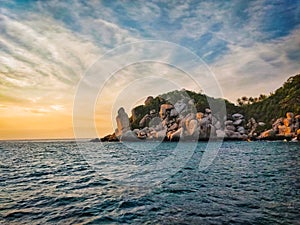 Epic sunset with beautiful orange red sun rays hitting on stones of a rocky island with blue sky and sea of Koh Tao Thailand. Koh