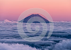 Epic sunset over volcano Mt. Fuji rising above an ocean of clouds. Seen from the summit of Mt. Kita