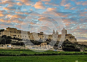 Epic sunset view of the Cathedral of St. Paul and skyline of medieval walled fortified city Mdina Rabat on the Mediterranean