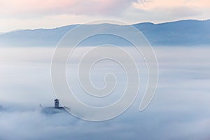 An epic view of St.Francis church in Assisi town Umbria above a sea of fog at dawn