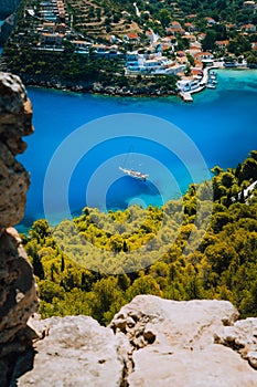 Epic view to blue bay of Assos village Kefalonia from Fortress above. White yacht at anchor in calm beautiful colored