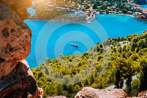 Epic view to blue bay of Assos village Kefalonia in warm morning sun light. White yacht at anchor in calm beautiful