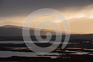 Epic Winter landscape image of view along Rannoch Moor during heavy rainfall giving misty look to the scene