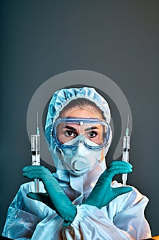 Epidemic of the Chinese coronavirus. A woman in a protective suit and mask holds an injection syringe and a virus vaccine in her