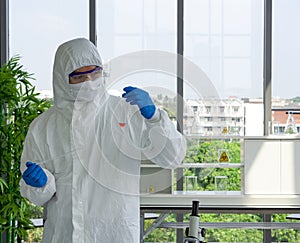 Epidemiological researcher in virus protective clothing use dropper to fill red liquid chemical into test tube. Coronavirus