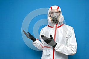 Epidemiologist in a chemical protective suit shows copyspace on a  background, man, biologist, scientist, virologist