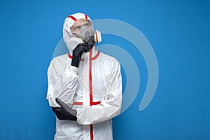 Epidemiologist in a chemical protective suit thinks and looks at copyspace on a isolated background, man, biologist, scientist,