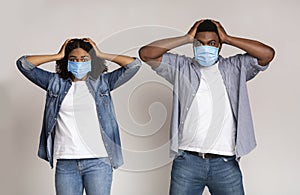 Epidemy Panic. Frightened Couple In Protective Masks Holding Head With Hands