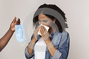 Epidemy Prevention. Male Hand Offering Protective Mask To Sick Black Woman