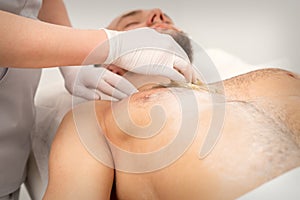 Epilation chest of a young male with the liquid wax paste in a beauty salon.