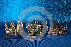 Epiphany Day or Dia de Reyes Magos concept. Three gold crowns on blue sparkling background