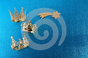 Epiphany Day or Dia de Reyes Magos concept. Three gold crowns on blue sparkling background