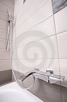 Epmty minimalistic interior background, bathroom of modern apartment, closeup of tap, shower and bathtub in light colors