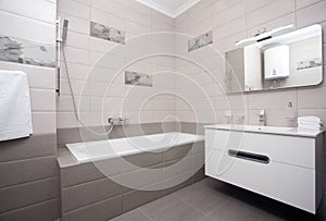 Epmty minimalistic interior background, bathroom of modern apartment, mirror, bathtub and basin in light colors