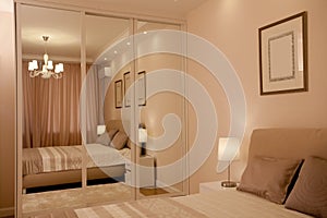 Epmty minimalistic interior background, bedroom of modern apartment with big mirrors, double bed, lights on