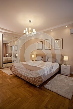 Epmty minimalistic interior background, bedroom of modern apartment with big mirrors, double bed, lights on