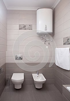 Epmty minimalistic interior background, toilet of modern apartment, lavatory and boiler in light colors