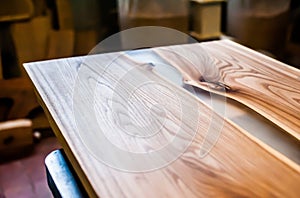 Epoxy-painted solid wood table top close-up in a carpentry workshop. Wood texture