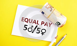 Eqaul pay 50 50 text written on a piece of paper with the zeros as the female and the male gender symbols, 50 euro banknote folded