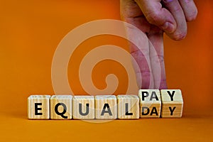 Equal pay day symbol. Businessman turns wooden cubes and changes words equal pay to equal day. Beautiful orange background. Copy