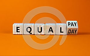 Equal pay day symbol. Turned the wooden cube and changed words equal pay to equal day. Beautiful orange background. Copy space.