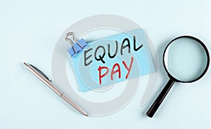 EQUAL PAY text written on a sticky with magnifier and pen, business concept